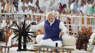 Prime Minister Narendra Modi spinning wheel during 'Khadi Utsav' in Ahmedabad on Saturday, August 27. (PTI)