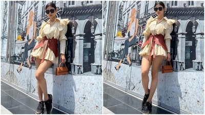 Mouni paired the mini dress with black tinted sunglasses, a tan mini top handle bag, and black sports shoes with front lace-up detail. A centre-parted sleek bun, mauve lip shade, and minimal makeup completed Mouni's glam picks with the ensemble. (Instagram/@imouniroy) Mouni paired the mini dress with black tinted sunglasses, a tan mini top handle bag, and black sports shoes with front lace-up detail. A centre-parted sleek bun, mauve lip shade, and minimal makeup completed Mouni's glam picks with the ensemble. (Instagram/@imouniroy)
