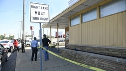 Polisi dan penyelidik Detroit melihat lokasi pembunuhan hari Minggu di Wyoming Avenue di sudut Seven Mile Road di Detroit.