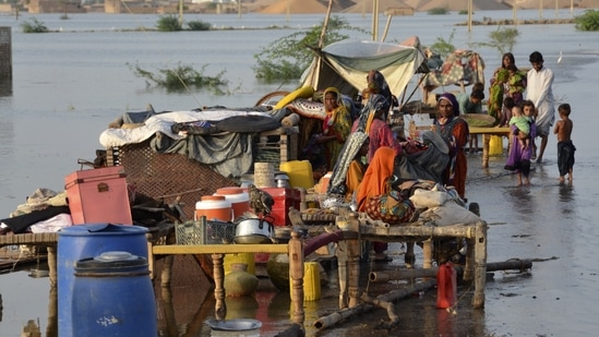 Families sit near their belongings surrounded by floodwaters, in Sohbat Pur city of Jaffarabad, a district of Pakistan's southwestern Baluchistan province, Sunday.&nbsp;(AP)