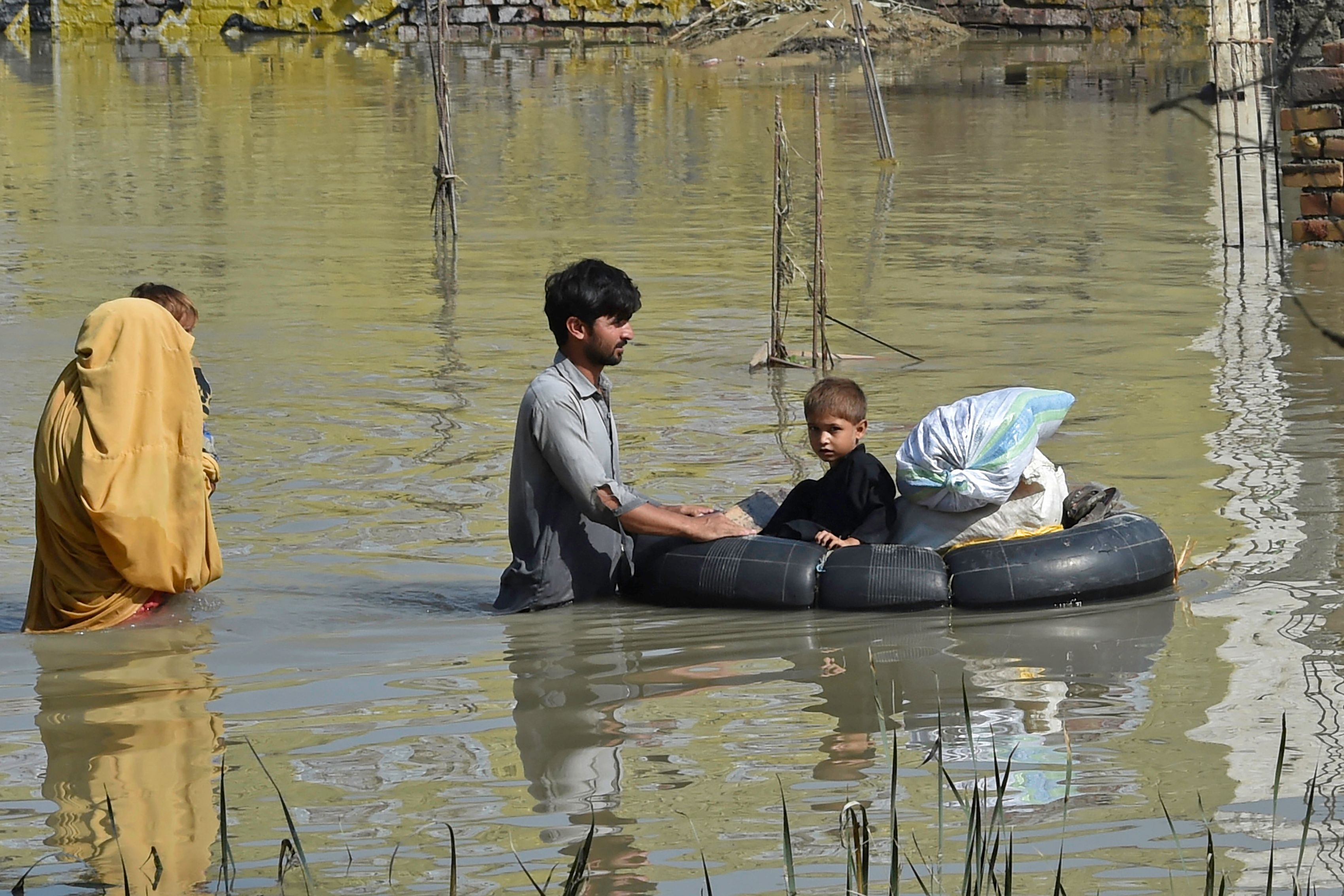 A family wades through a flood-hit area following heavy monsoon rains in Charsadda district of Khyber Pakhtunkhwa.&nbsp; (AFP)