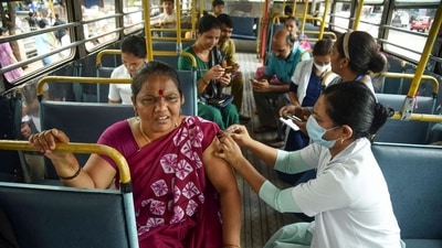 A Navi Mumbai Municipal Corporation worker administers precautionary booster dose of COVID-19 vaccine to a beneficiary, inside a bus in Navi Mumbai. (PTI) A Navi Mumbai Municipal Corporation worker administers precautionary booster dose of COVID-19 vaccine to a beneficiary, inside a bus in Navi Mumbai. (PTI)