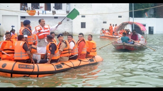 Deputy CM Keshav Prasad Maurya on a boat distributing relief to flood-affected people in Prayagraj on Tuesday. (HT)