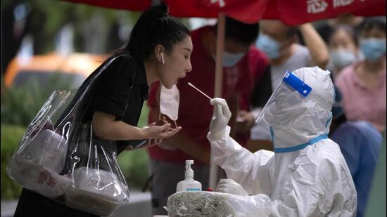 A worker wearing a protective suit swabs a woman’s throat for a Covid-19 test at a coronavirus testing site in Beijing, China on Friday. (AP)