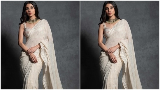 Mouni Roy's ivory saree comes decked with sequin embellishments and scalloped gota patti embroidered on the border adorned with shimmering beads. The star draped the six yards in traditional style around her body, letting the pallu fall from her shoulder in a floor-grazing train.(Instagram)