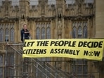 A Extinction Rebellion protester sits next to a banner outside the Palace of Westminster, where inside the House of Commons, ER protesters have glued themselves to the Speakers Chair in London, Friday, A Extinction Rebellion protester sits next to a banner outside the Palace of Westminster, where inside the House of Commons, ER protesters have glued themselves to the Speakers Chair in London, Friday, 