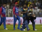 Sri Lanka's Chamika Karunaratne, right, Wanindu Hasaranga, second right, and Afghanistan's Mohammad Nabi, center, and Hazratullah Zazai, walk off the filed on the end of the T20 cricket match.(AP)