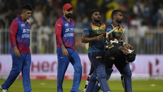 Sri Lanka's Chamika Karunaratne, right, Wanindu Hasaranga, second right, and Afghanistan's Mohammad Nabi, center, and Hazratullah Zazai, walk off the filed on the end of the T20 cricket match.(AP)