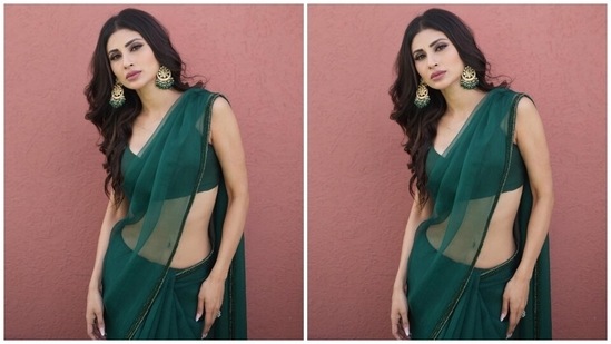 Mouni wore the sheer saree with a matching green blouse featuring spaghetti straps, a plunging neckline showing off her décolletage, cropped hem length and bodycon fitting. A pair of ornate gold jhumkis with emerald green beads, rings, and high heels completed the look.(Instagram)