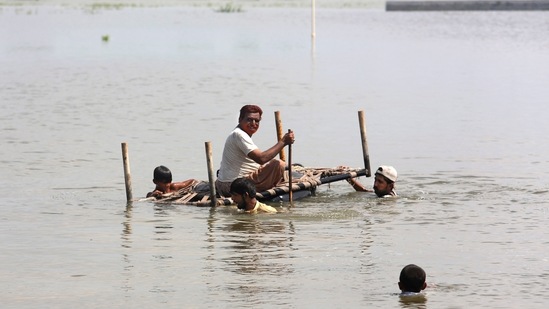 People use cot to salvage belongings from their nearby flooded home caused by heavy rain.(AP)