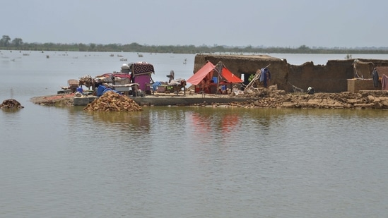 A family sit under a tent in their damaged home surrounded by flood, in Jaffarabad, a district of Pakistan's southwestern Baluchistan province, Saturday.(AP)