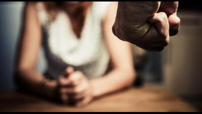 Young woman is sitting hunched at a table at home, the focus is on a man's fist in the foregound of the image (Getty Images/iStockphoto) Young woman is sitting hunched at a table at home, the focus is on a man's fist in the foregound of the image (Getty Images/iStockphoto)