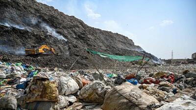 A man segregates plastic, polythene and other reusable materials from waste collected by ragpickers as smoke billows during an ongoing fire at Bhlaswa landfill seen in the background in New Delhi on June 4, 2022. (Photo by Prakash SINGH / AFP) (AFP) A man segregates plastic, polythene and other reusable materials from waste collected by ragpickers as smoke billows during an ongoing fire at Bhlaswa landfill seen in the background in New Delhi on June 4, 2022. (Photo by Prakash SINGH / AFP) (AFP)