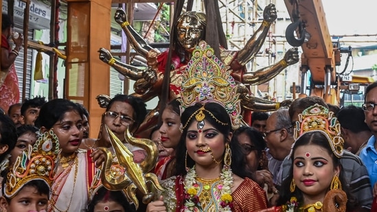 Devotees gather near an idol of goddess Durga made of alloy consisting of eight different metals and weighing around one metric tonne as it is being placed inside a pandal or a fabricated structure by a crane ahead of the Durga Puja festival in Kolkata.(AFP)