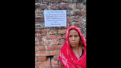 A resident of Sapaha village in Kushinagar district shows the sale poster pasted on her house wall (HT Photo)