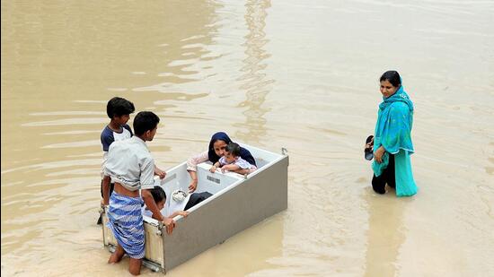 Residents of a waterlogged locality try to reach a safer place with making sit their children in a fridge following heavy rains, in Bengaluru on Tuesday (ANI)