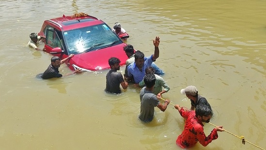 People pull a car in water-logged Bengaluru on Monday.&nbsp;(REUTERS)