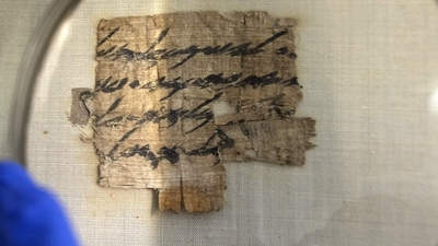 An Israel Antiquities Authority conservator views under a magnifying glass a papyrus fragment. (AFP) An Israel Antiquities Authority conservator views under a magnifying glass a papyrus fragment. (AFP)