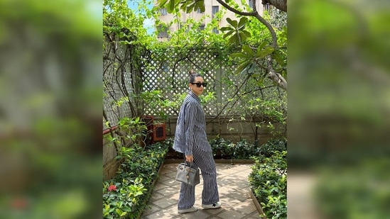 Karisma Kapoor amped up her look by accessorising her outfit with a pair of black sunglasses and a grey handbag.(Instagram/@therealkarismakapoor)