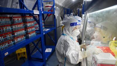 Staff members of Sichuan Provincial People's Hospital test nucleic acid samples inside a mobile laboratory set up at a sports centre, following Covid-19 outbreak in Chengdu, Sichuan province, China. (REUTERS)