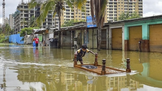 A boy pushes a table in a flooded locality of Bellandur after heavy monsoon rains, in Bengaluru. (PTI)