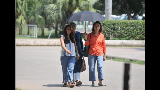 Students using an umbrella for some respite from the scorching sun at Panjab University, Chandigarh, on Thursday. (Ravi Kumar/HT)