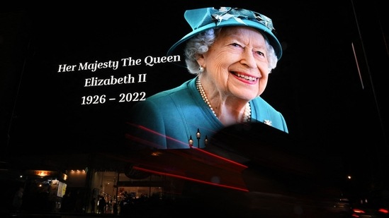 Members of the public stop in the rain to study a huge picture of Britain's Queen Elizabeth II displayed at Piccadilly Circus in central London on September 8, 2022, after the announcement of her death. (Photo by Ben Stansall/AFP)