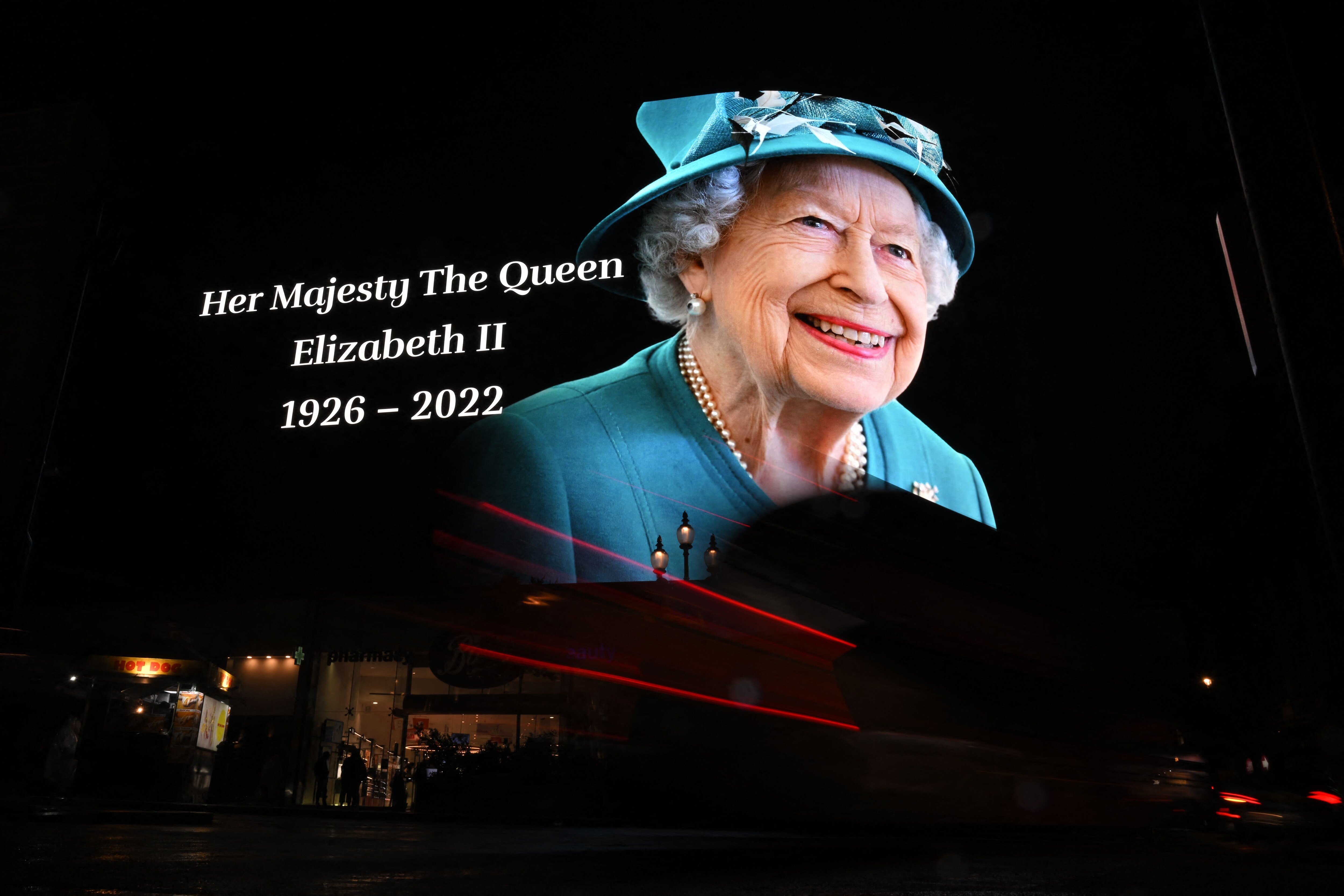 Members of the public stop in the rain to study a huge picture of Britain's Queen Elizabeth II displayed at Piccadilly Circus in central London on September 8, 2022, after the announcement of her death. (Photo by Ben Stansall/AFP) Members of the public stop in the rain to study a huge picture of Britain's Queen Elizabeth II displayed at Piccadilly Circus in central London on September 8, 2022, after the announcement of her death. (Photo by Ben Stansall/AFP)