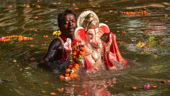 A devotee immerses an idol of Lord Ganesha in the Gomti river during 'Gauri Ganpati Visarjan' in Lucknow.(PTI)