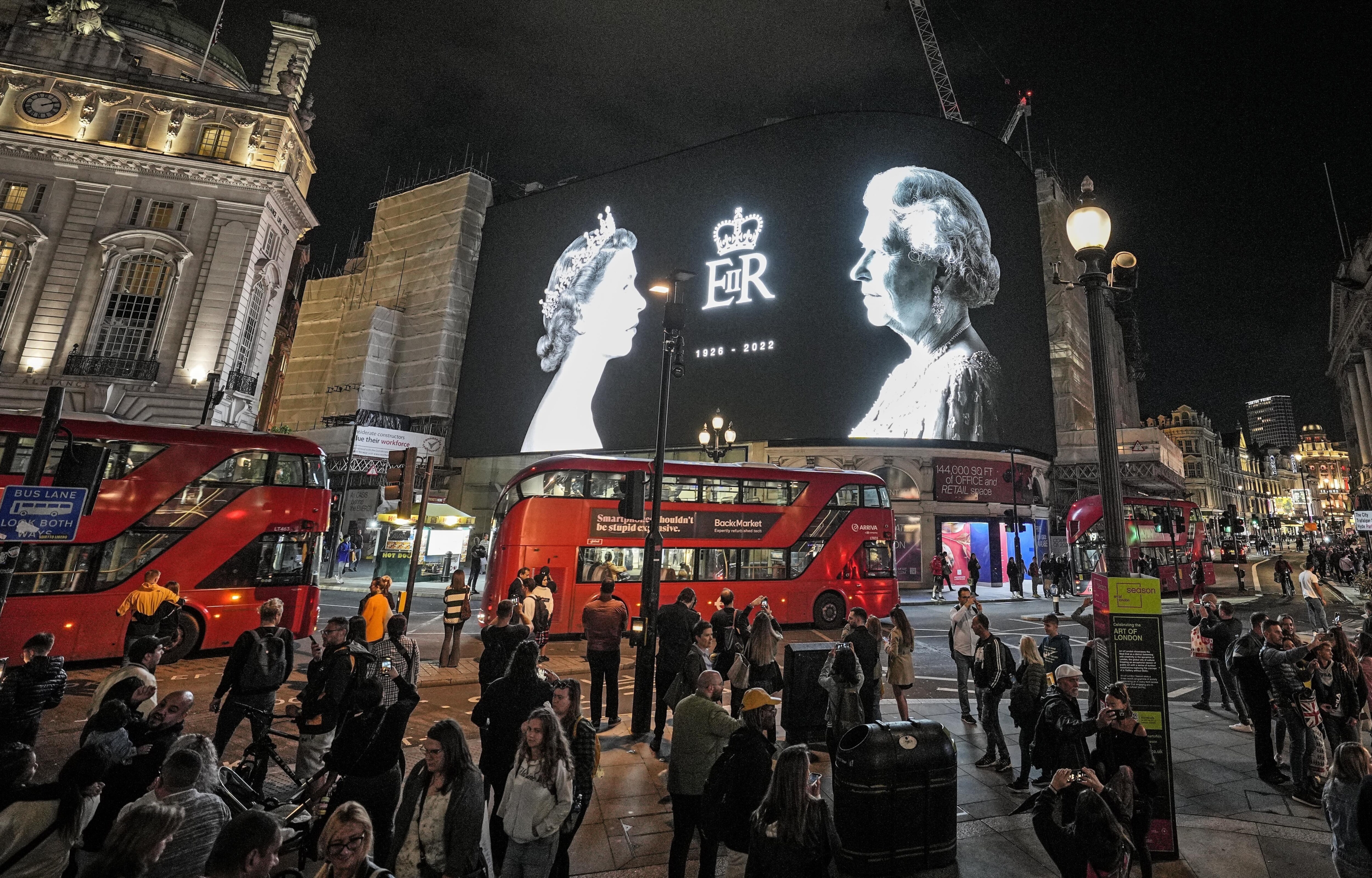 A big screen displays photos of Queen Elizabeth II at Piccadilly Circus in London, Friday, September 9, 2022. (AP Photo/Martin Meissner)