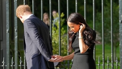 Prince Harry and Meghan Markle hold hands as they view the floral tributes for the late Queen Elizabeth II outside Windsor Castle, in Windsor.&nbsp; (AP)