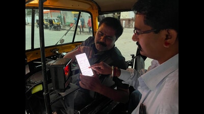 An auto rickshaw driver shows a tariff card to a passenger on his mobile phone on Sunday. (Rahul Raut/HT PHOTO)