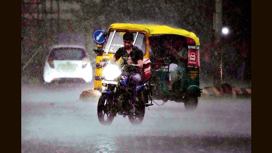 A man rides a two-wheeler in the rain in Ahmedabad. (AP)