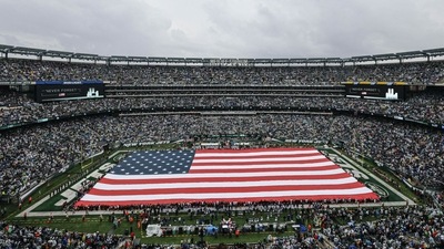 An American flag covers the field at MetLife Stadium as the main scoreboard honors the victims of 9/11 before the game between the New York Jets and the Baltimore Ravens. (Vincent Carchietta/USA TODAY Sports)