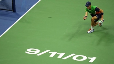 A ball person rolls a ball to the baseline across a logo commemorating the anniversary of the attacks on 9/11 during the match between Carlos Alcaraz (ESP) and Casper Ruud (NOR) in the men's singles final of the U.S. Open tennis tournament. (Danielle Parhizkaran/ USA TODAY Sports)