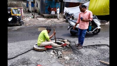 A civic staff cleans a choked drainage at Dolphin chowk, Upper Indiranagar on Monday. (Rahul Raut/HT PHOTO)