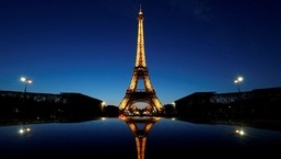 Uma visão noturna mostra a Torre Eiffel, refletida no teto de um carro, em Paris, França.