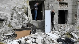 Guerra Rússia-Ucrânia:  Moradores locais ficam do lado de fora de seu prédio parcialmente destruído por um ataque com mísseis em Kharkiv.