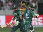Sri Lanka's Dilshan Madushanka, center, watches as Pakistan's captain Babar Azam, left, and Mohammad Rizwan run between the wickets.