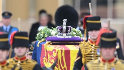 The coffin of Queen Elizabeth II, adorned with a Royal Standard and the Imperial State Crown and pulled by a Gun Carriage of The King's Troop Royal Horse Artillery, is pictured during a procession from Buckingham Palace to the Palace of Westminster, in London. (AFP)