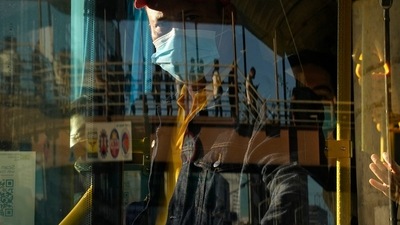 A bus attendant waits for passengers at a bus stop. (AP)