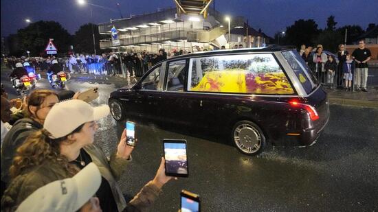 People take pictures of the State Hearse carrying the coffin of Queen Elizabeth II on the way from RAF Northolt to Buckingham Palace in London, England, on Tuesday. (AP)