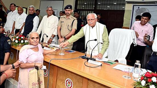 Haryana chief minister Manohar Lal Khattar while giving a pension of <span class='webrupee'>?</span>2,500 from his pocket to an elderly woman during the mass dialogue program organised in Rohtak. He immediately ordered the officers to restore the pension of the elderly woman. (Manoj Dhaka/HT)