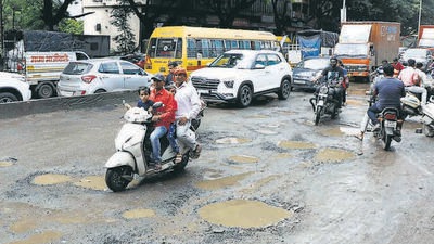 Residents make way through a pothole-ridden Kondhwa road near Khadi Machine chowk on Saturday. (Rahul Raut/HT PHOTO)