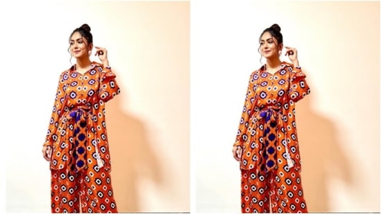 Mrunal looked gorgeous in the orange jumpsuit featuring geometric patterns in white and blue. The jumpsuit came with fluffy full sleeves, wide legs and a belt detail at the waist.(Instagram/@mrunalthakur)