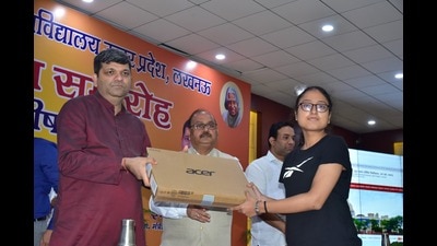 Ashish Patel, minister of technical education gifting laptop to a student at AKTU on Sunday. (HT PHOTO)