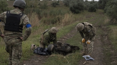 Russia-Ukraine War: Ukrainian servicemen examine the body of a Ukrainian soldier in a retaken area near the border with Russia in Kharkiv region. (AP) Russia-Ukraine War: Ukrainian servicemen examine the body of a Ukrainian soldier in a retaken area near the border with Russia in Kharkiv region. (AP)