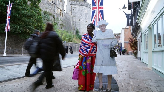 A member of the public standing next to a cardboard cut out of Queen Elizabeth II in Windsor, England ahead of the state funeral.(AP)