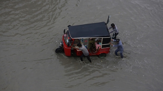 FILE - People push a rickshaw through a flooded road after a heavy rainfall in Karachi, Pakistan. (AP)
