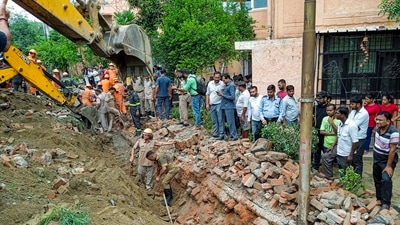 Noida: Rescue operation underway after a portion of a boundary wall of a housing society collapsed, at Jal Vayu Vihar in Noida, Tuesday, (PTI Photo) Noida: Rescue operation underway after a portion of a boundary wall of a housing society collapsed, at Jal Vayu Vihar in Noida, Tuesday, (PTI Photo)